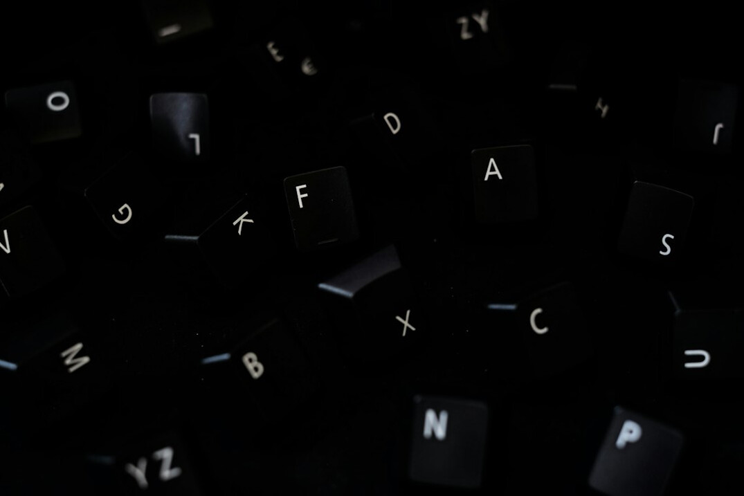 Close-up of hands typing on a laptop keyboard with code on screen